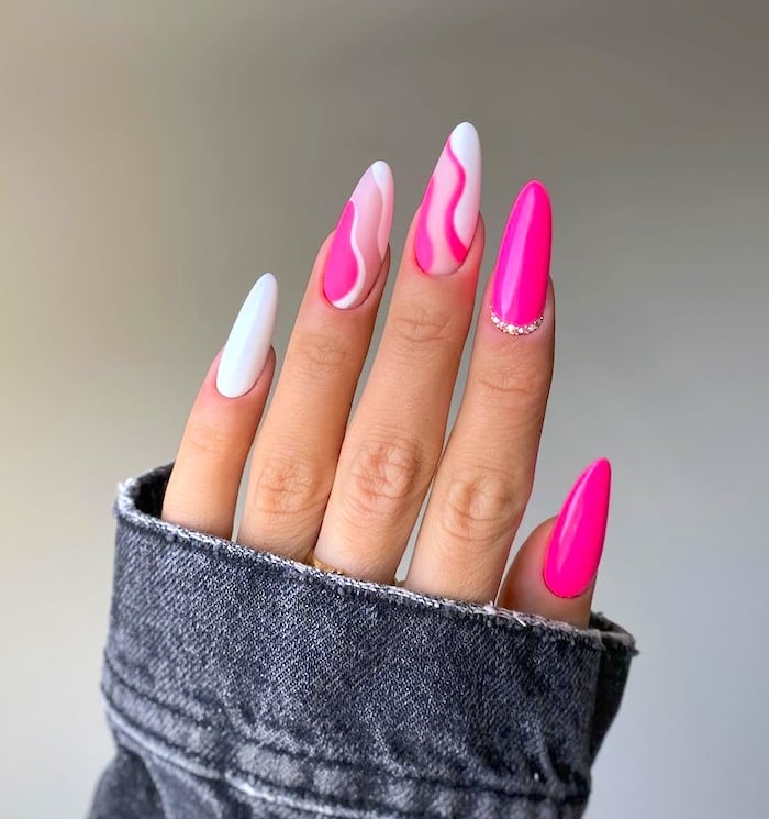 White and bright pink nails and dark denim sleeve.