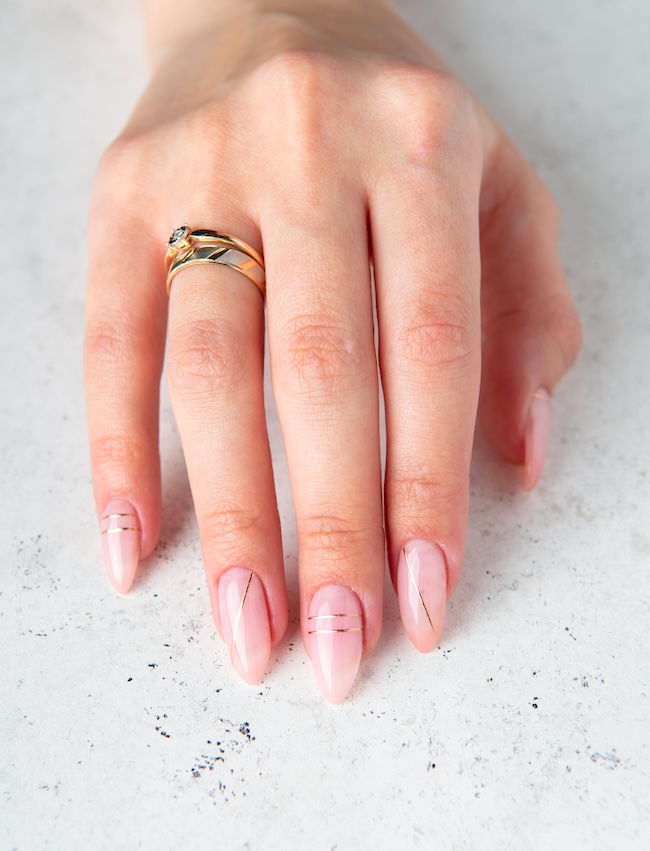 Pink minimalist nails with thin gold lines.