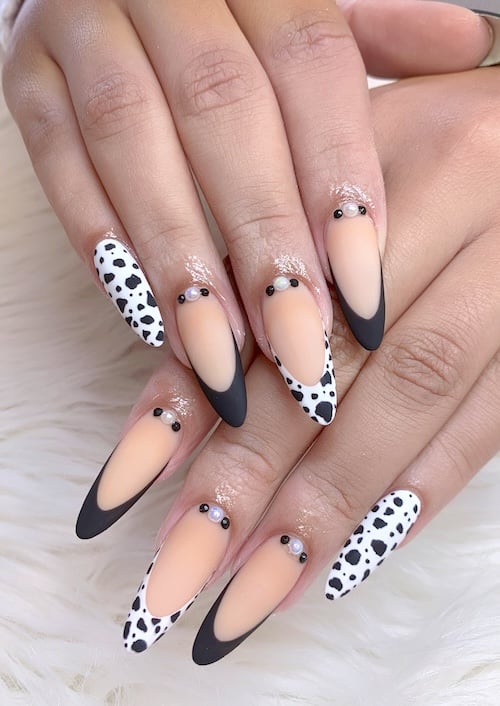 Cow print, nude and French tip almond nails.