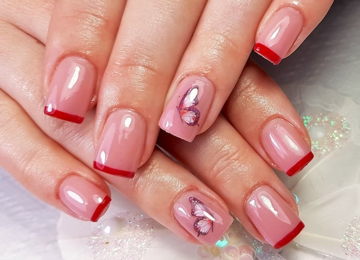 Red French tip nails with butterflies.