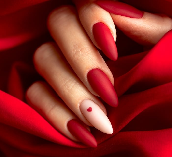 Matte red nails with heart nail art.