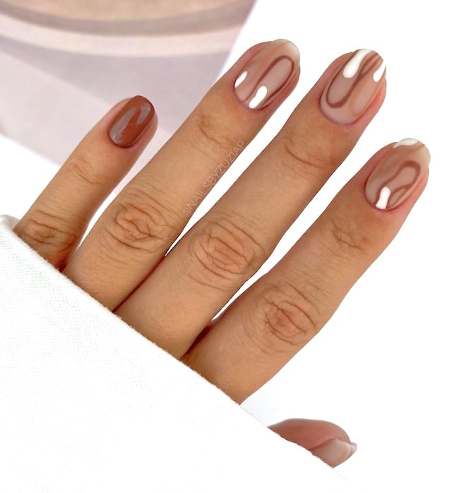 Nude nails with brown swirls.