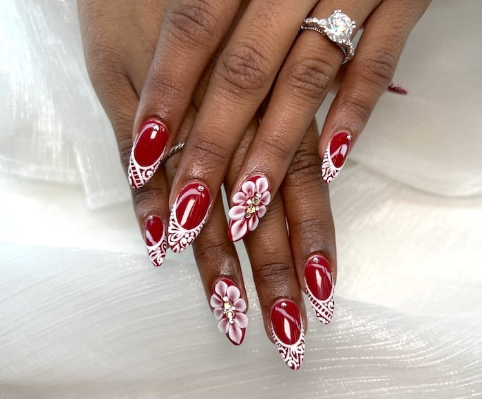 Red nails with white 3D flower nail art.