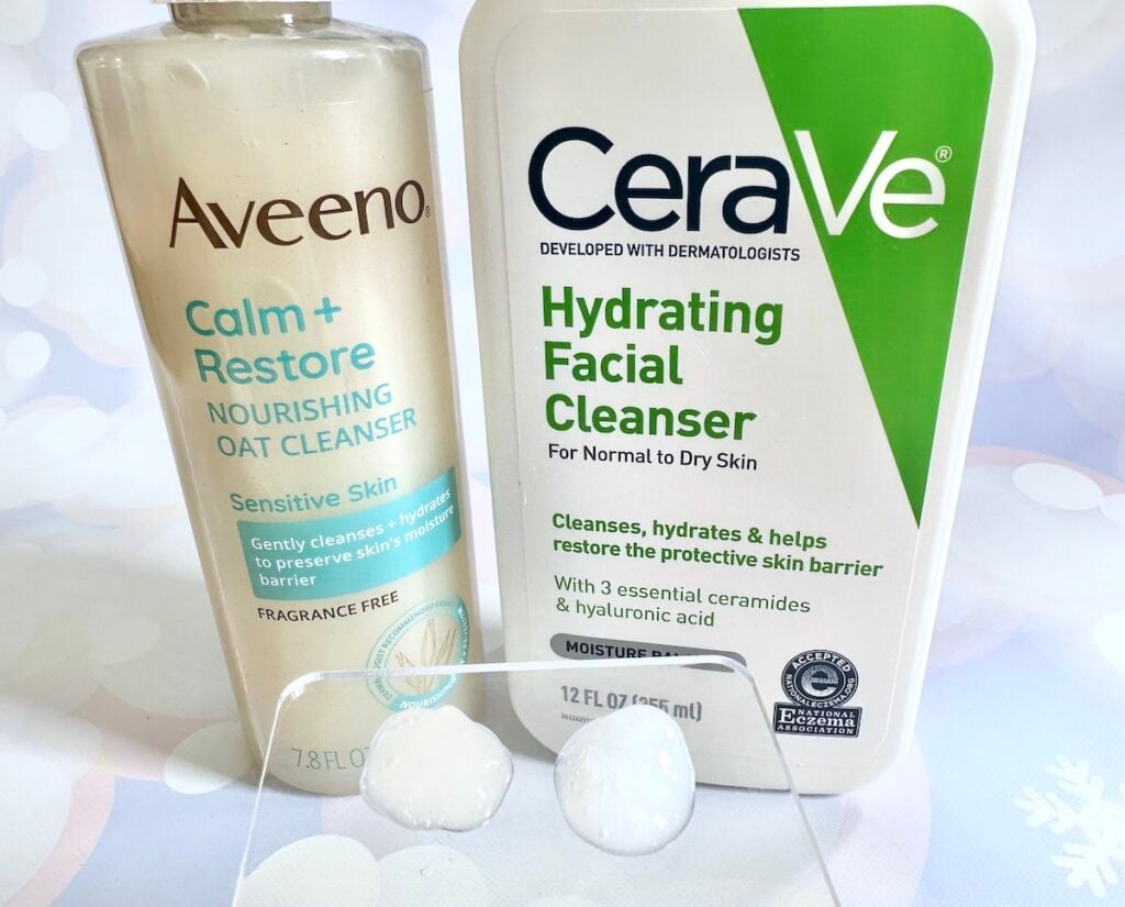 Aveeno Calm + Restore Gentle Nourishing Oat Cleanser vs CeraVe Hydrating Facial Cleanser behind samples on clear spatula.