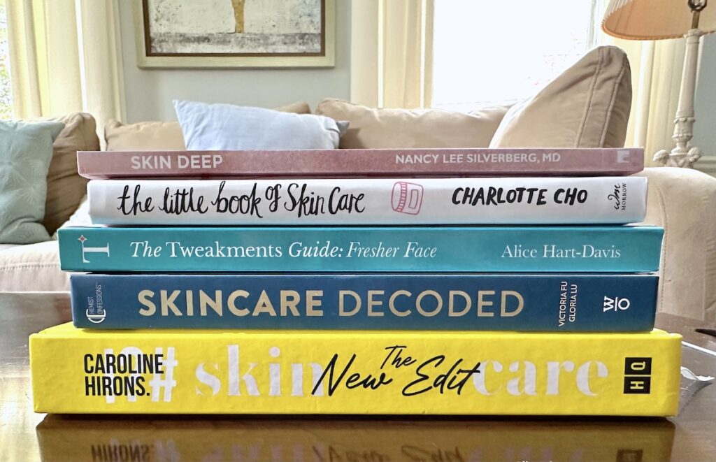 Best skincare books stacked spines on coffee table in living room.