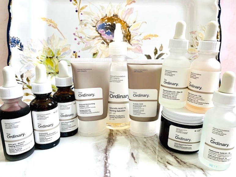 Best The Ordinary products for acne and oily skin on marble and flower background: serums, cleanser, toner, treatments, and moisturizer.