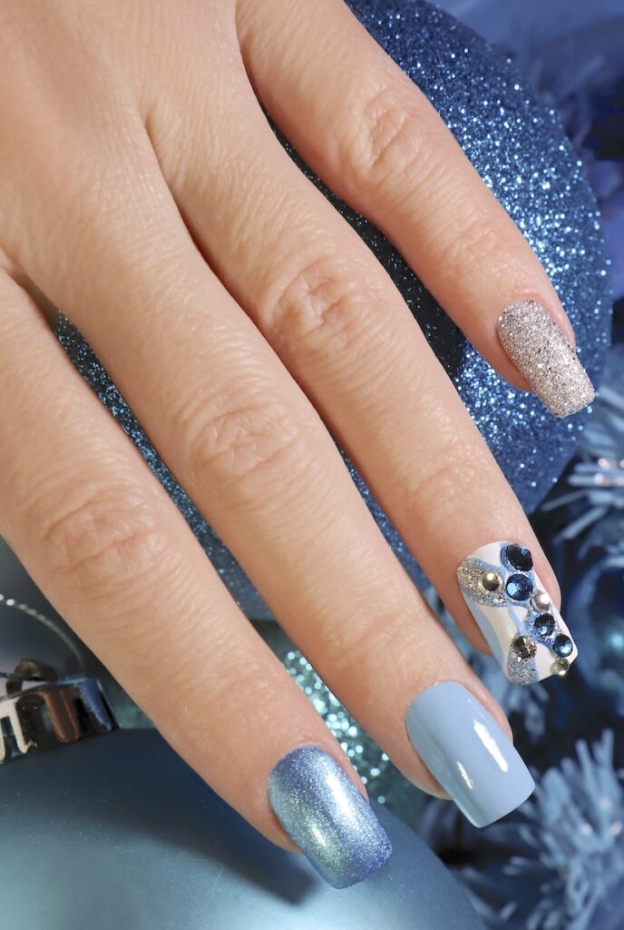 Sparkly blue winter nails design with rhinestones.