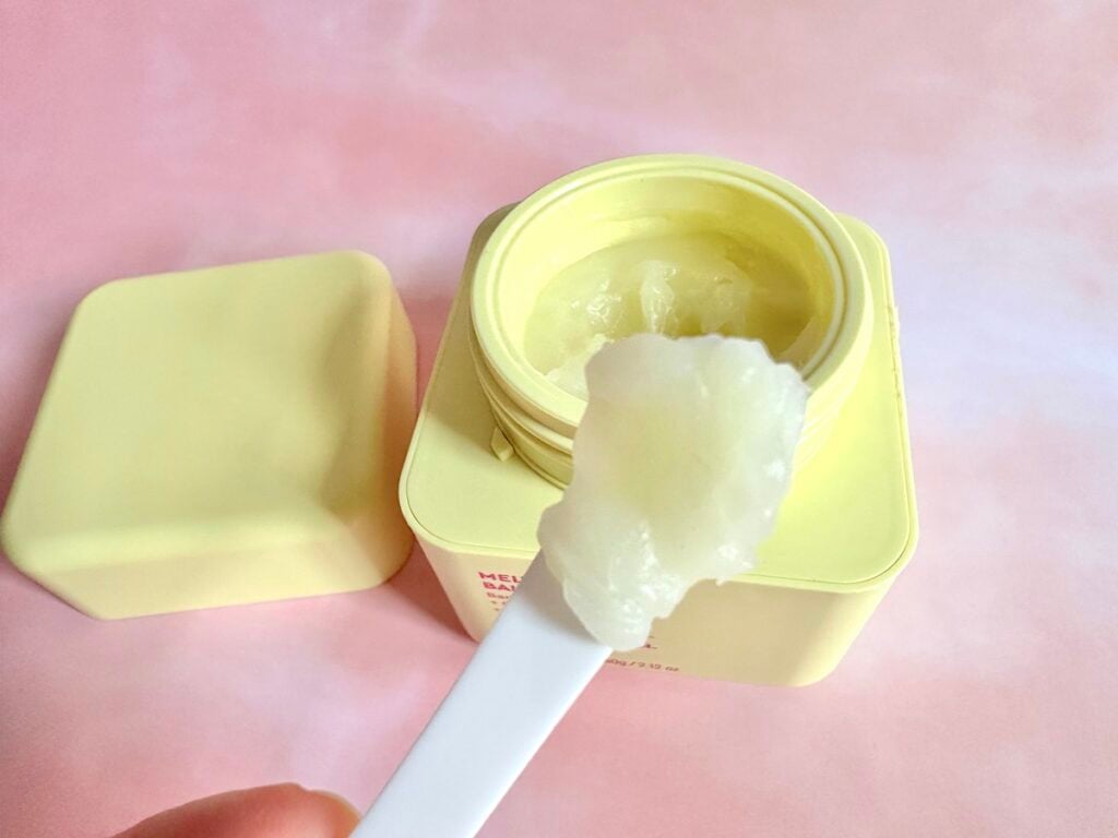 Byoma Melting Balm Cleanser, open jar with sample on white cosmetic spatula.