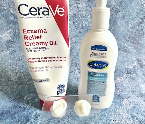 CeraVe Eczema Relief Creamy Oil and Cetaphil Eczema Restoraderm Soothing Moisturizer bottles, next to samples on clear spatula.