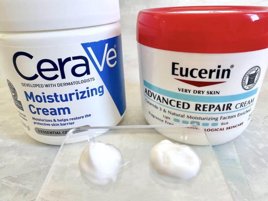 Cerave Moisturizing Cream and Eucerin Advanced Repair Cream jars, sampled on spatula.