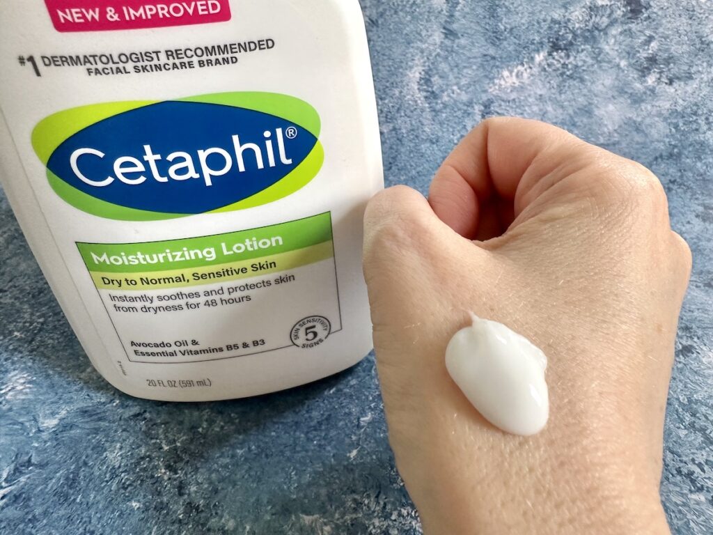 Cetaphil Moisturizing Lotion bottle, next to lotion sampled on back of hand.