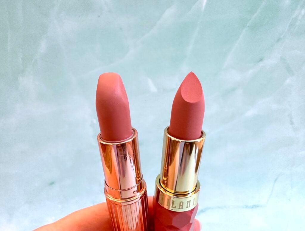 Charlotte Tilbury Pillow Talk Lipstick and Milani Color Fetish Matte Lipstick in the shade Secret, open tubes, handheld.