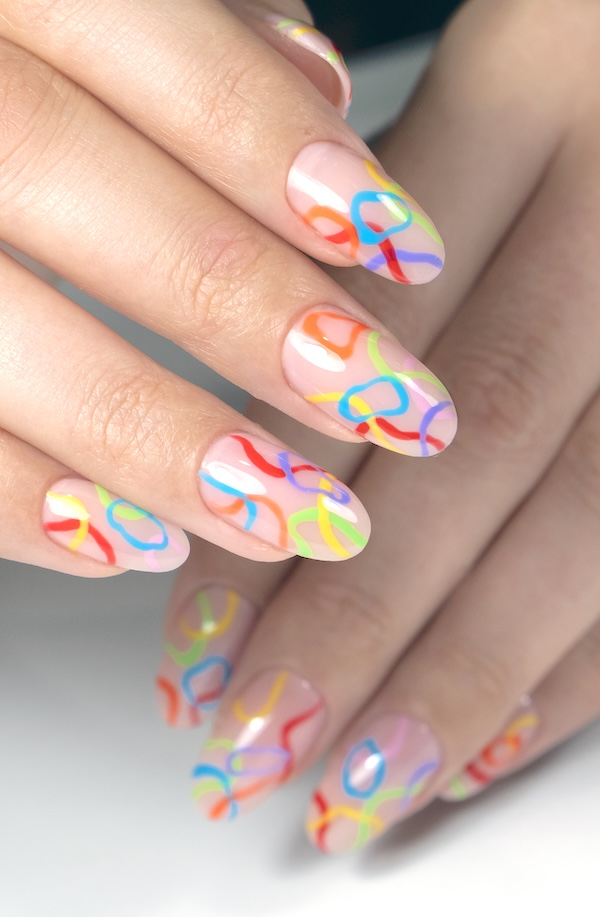 Mulit-colored rainbow rings on pink nail base.