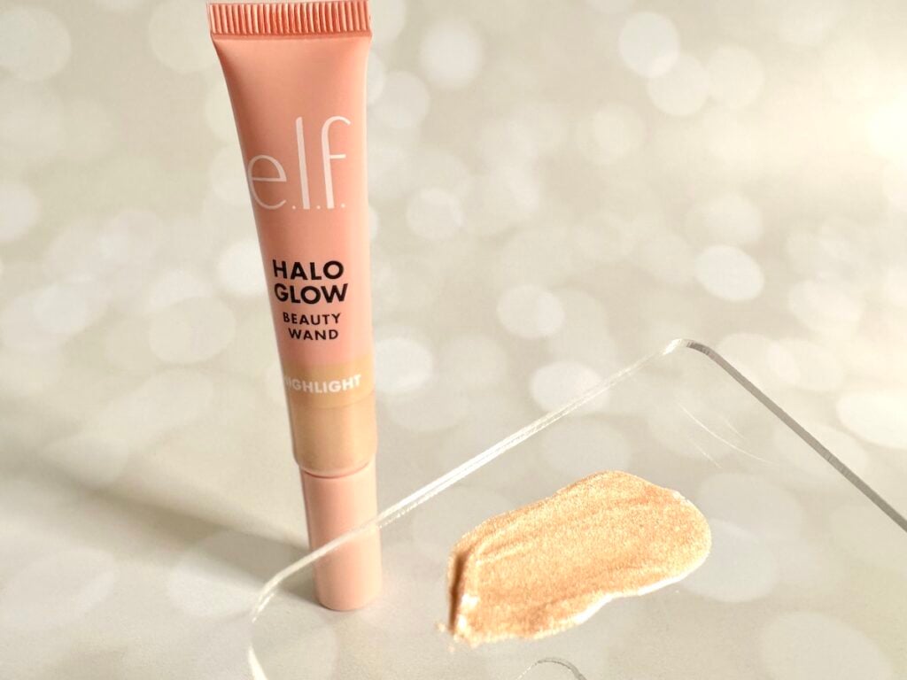 e.l.f. Halo Glow Highlight Beauty Wand in the shade Champagne Campaign next to highlighter sample on clear plastic spatula.