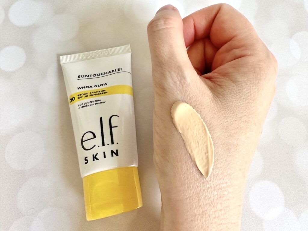 e.l.f. Suntouchable! Whoa Glow SPF 30 Sunscreen & Primer flatlay next to sample on hand.