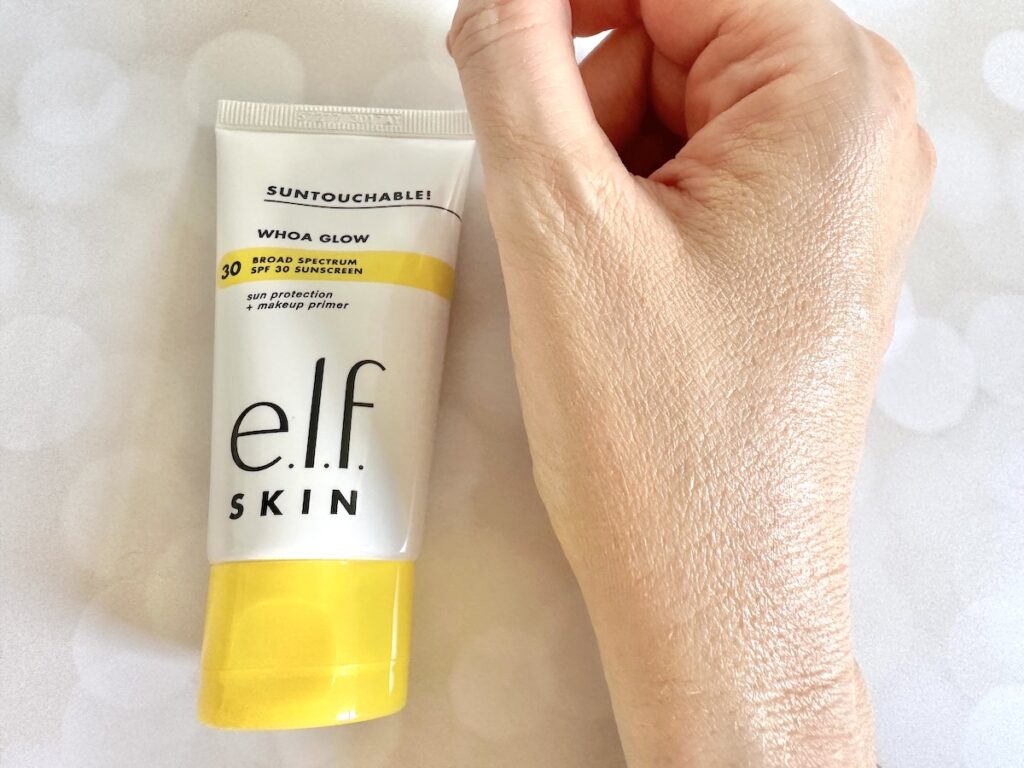 e.l.f. Suntouchable! Whoa Glow SPF 30 Sunscreen & Primer flatlay next to sample on hand, absorbed.