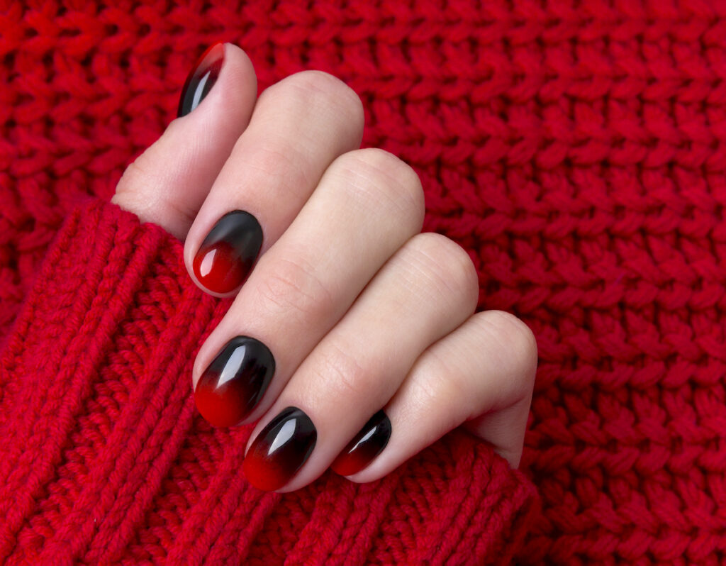 Red and black fall ombre nail with red sweater background.