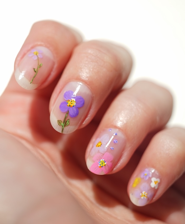 Pressed flowers nail art on natural nail background.