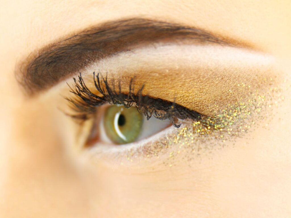 Golden glitter eyeshadow on a green eye.