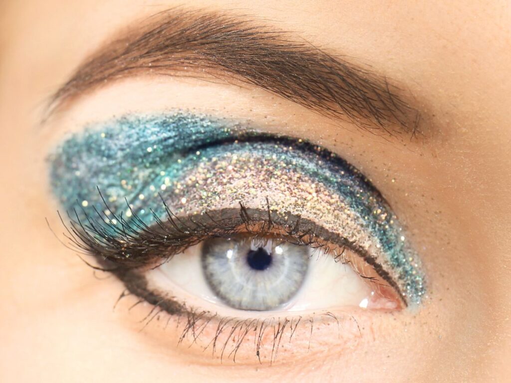 Aqua and gold glittery eyeshadow on a pale blue eye.