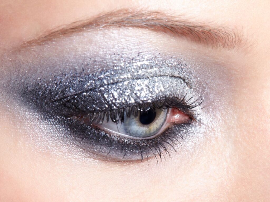 Glittery silver eyeshadow and a deep gray winged eye liner look.