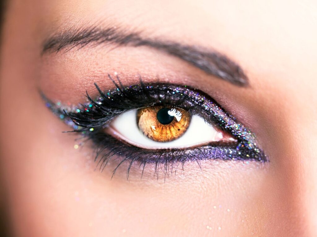 Multi-color glitter and black and purple eyeliner framing a light brown eye.