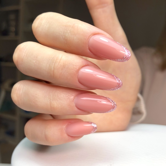 Glittery pink French tip nails.