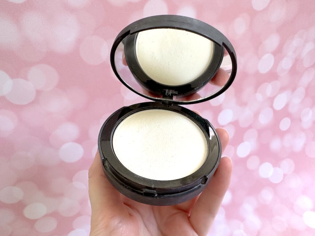 It Cosmetics Bye Bye Pores Poreless Finish Airbrushed Pressed Powder in the shade Translucent, handheld.