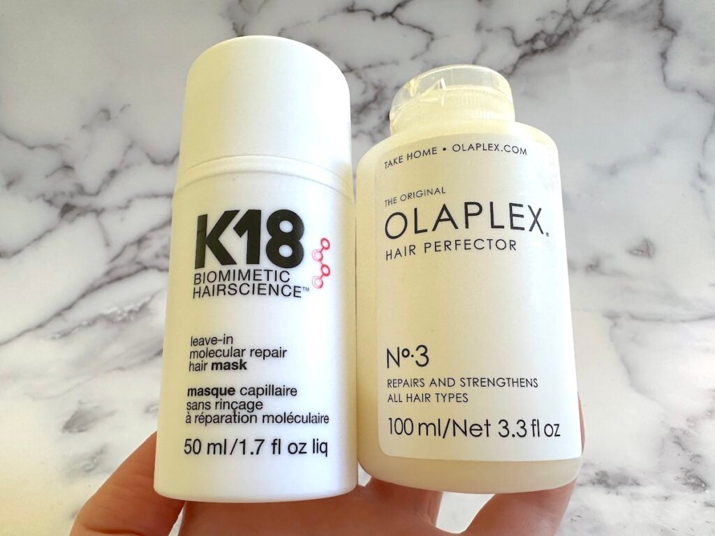 K18 Leave-In Molecular Repair Hair Mask and Olaplex No.3 Hair Perfector handheld.