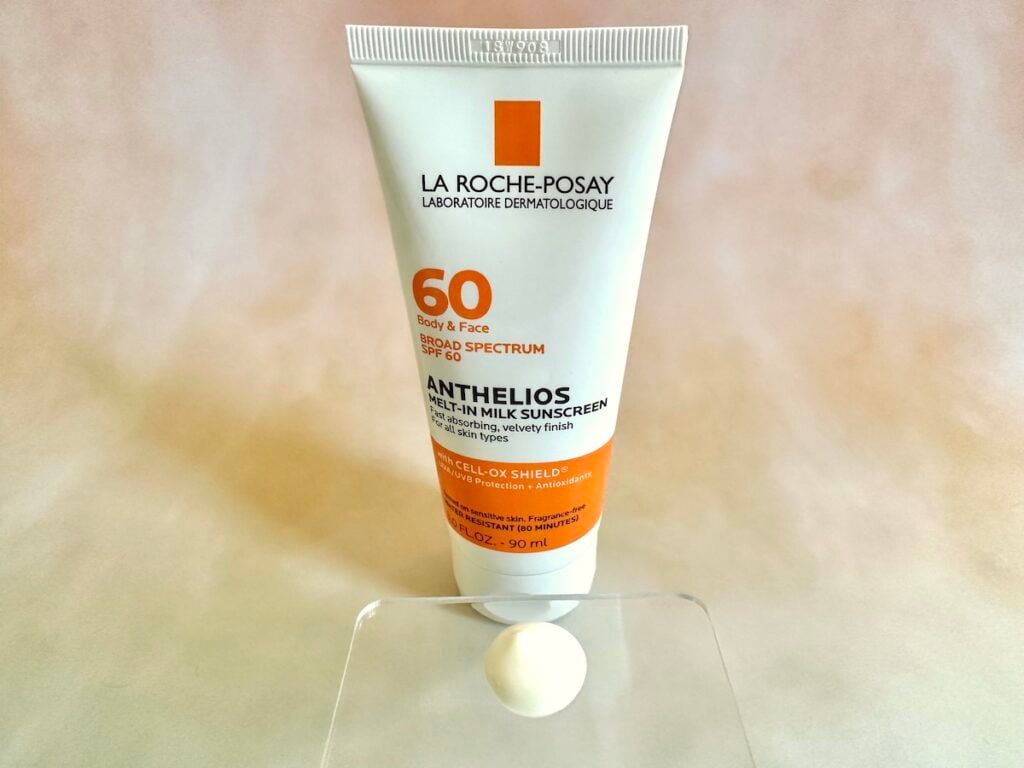 La Roche-Posay Anthelios Melt-In Milk Sunscreen SPF 60, tube behind sunscreen sample on clear plastic spatula.