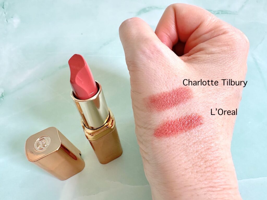 L’Oreal Paris Color Riche Les Nus Satin Lipstick in 171 Confident tube, next to sample of Charlotte Tilbury Pillow Talk Lipstick and L'Oreal on handheld.