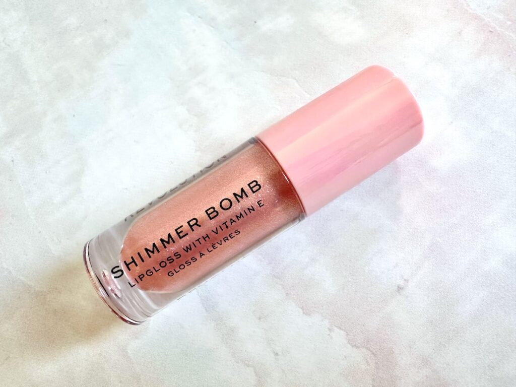 Makeup Revolution Shimmer Bomb Lip Gloss in the shade Glimmer, flatlay.