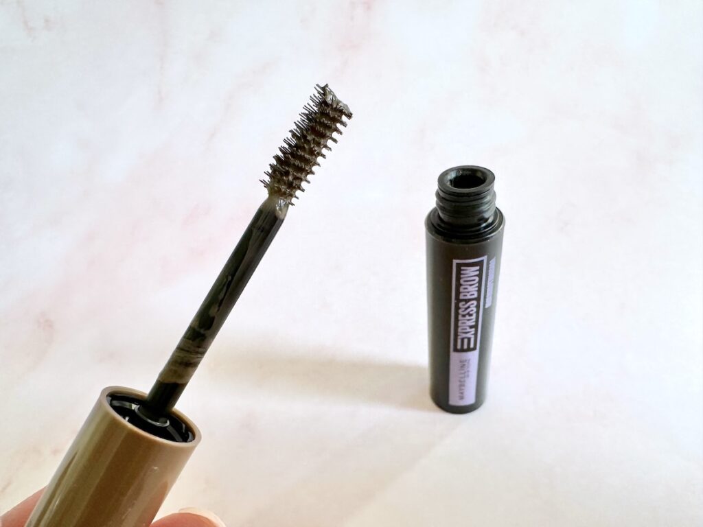 Maybelline Express Brow Fast Sculpt Mascara in the shade Soft Brown, open tube with applicator wand, handheld.