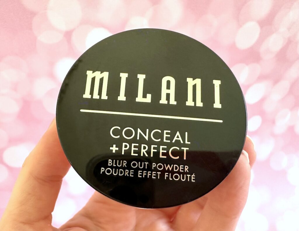 Milani Conceal + Perfect Blur Out Powder in the shade Translucent, handheld.