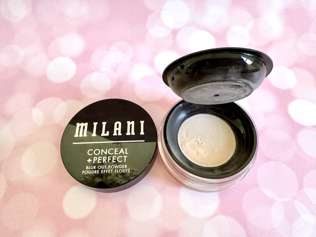 Milani Conceal + Perfect Blur Out Powder in the shade Translucent, open jar flatlay with lid.