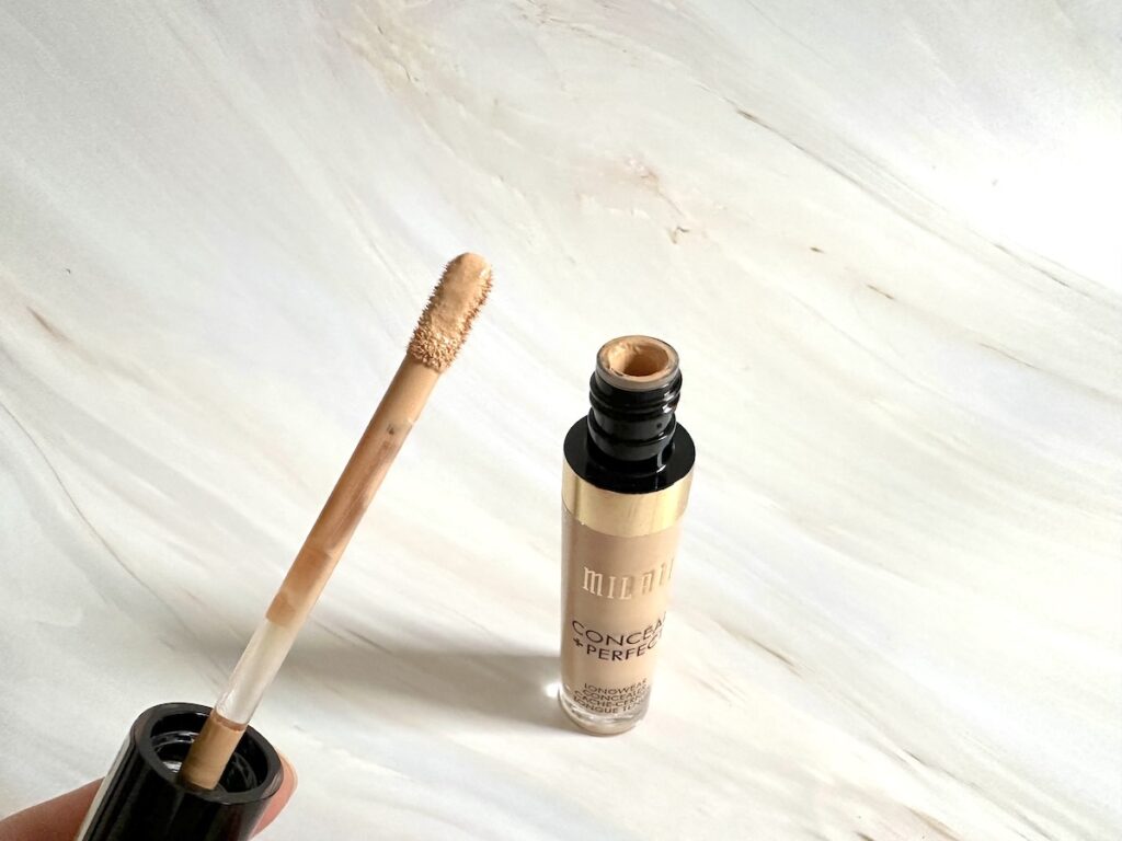 Milani Conceal + Perfect Concealer in the shade Light Beige, open tube with applicator wand, handheld.