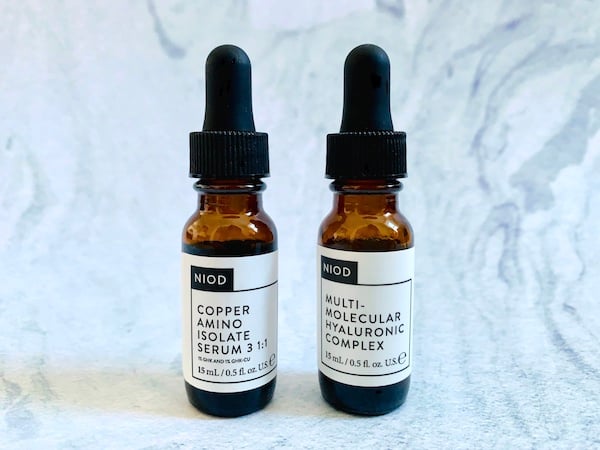 NIOD Copper Amino Isolate Serum 3 1:1 and NIOD Multi-Molecular Hyaluronic Complex on blue background