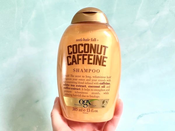 OGX Anti-Hair Fall + Coconut Caffeine Strengthening Shampoo, handheld.