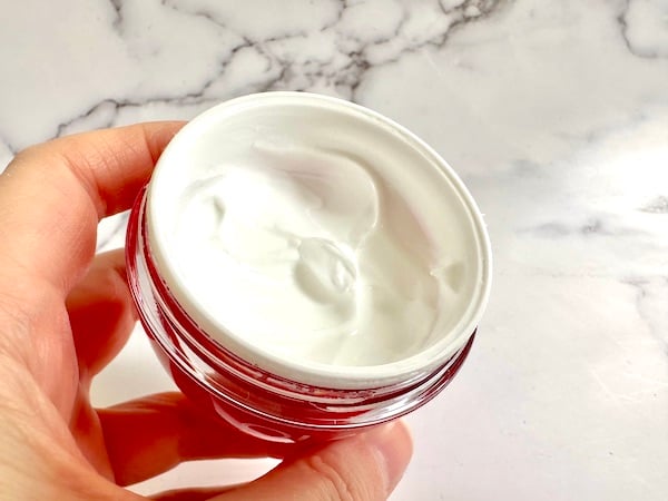 Olay Niacinamide + Peptide 24 Moisturizer, open jar, handheld.