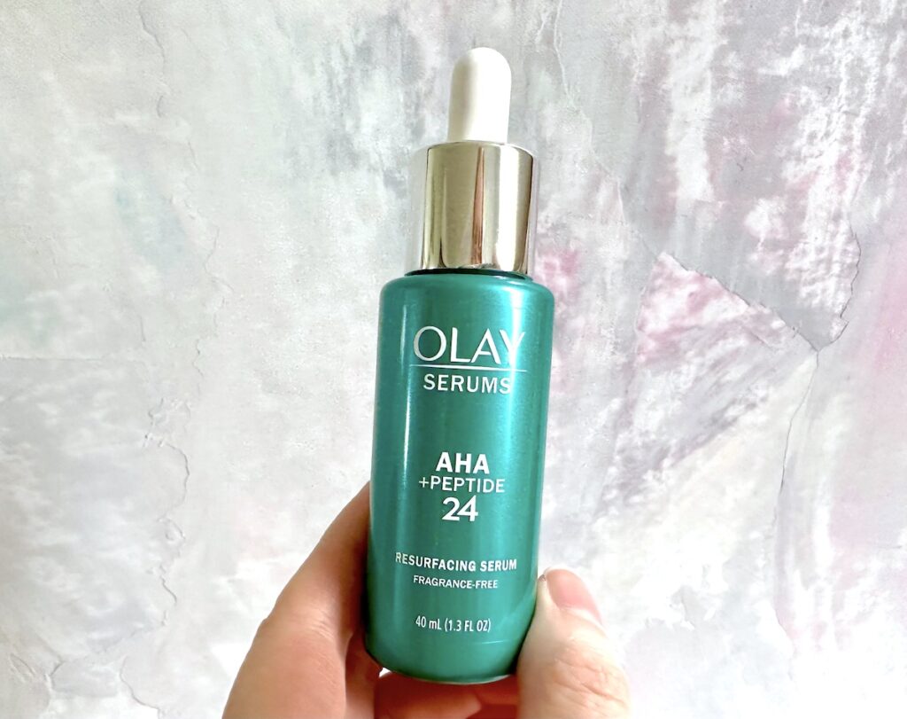 Olay AHA + Peptide 24 Serum, handheld.