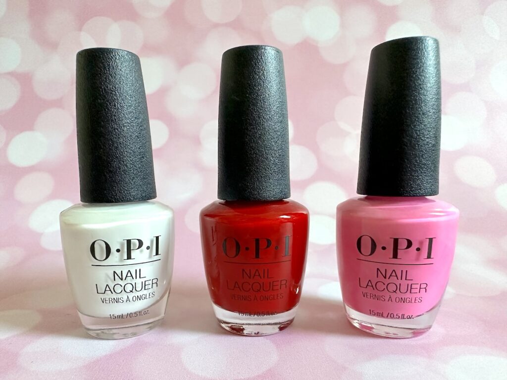 OPI nail lacquers in the shades Alpine Snow, Apple Red, and Makeout-side.