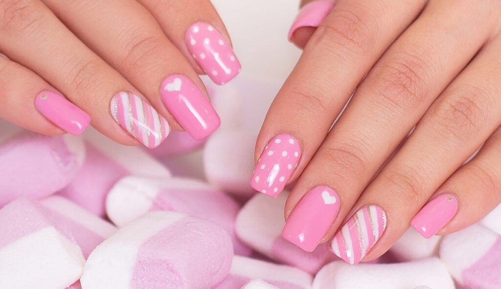 Pink and white nails next to pink and white candies.