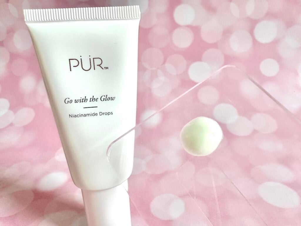 PUR Go with the Glow Niacinamide Drops, tube next to sample on clear plastic cosmetic spatula.