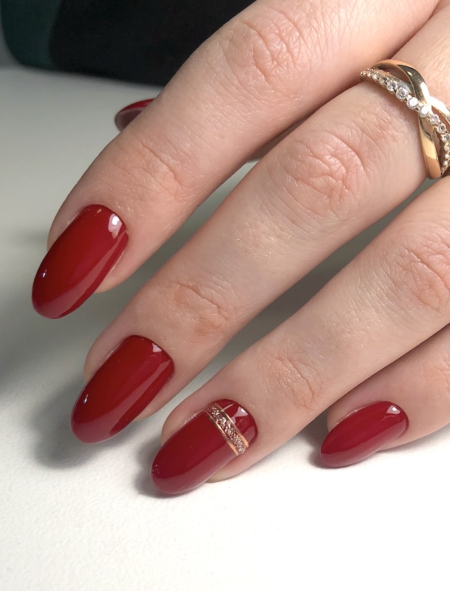 Red almond nails with glittery gold line.