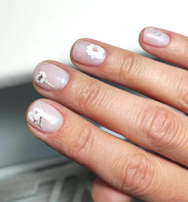 Floral accents on short pale pink nails.