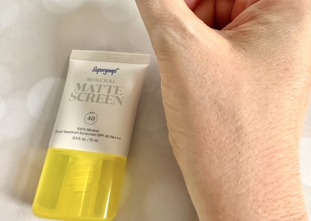 Supergoop! Mineral Mattescreen SPF 40, flatlay of tube next to sample absorbed on hand.