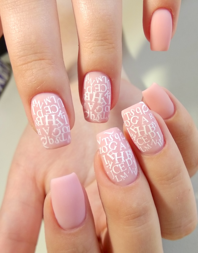 Pink with white text on square nails.