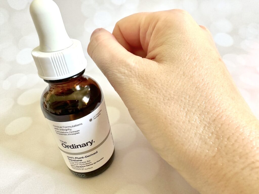 The Ordinary 100% Plant-Derived Squalane, bottle next to sample absorbed on hand.