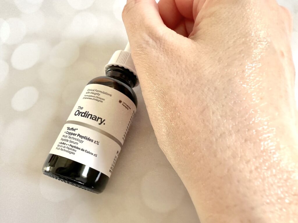 The Ordinary "Buffet" + Copper Peptides 1% Serum, bottle flatlay with sample absorbed on hand.