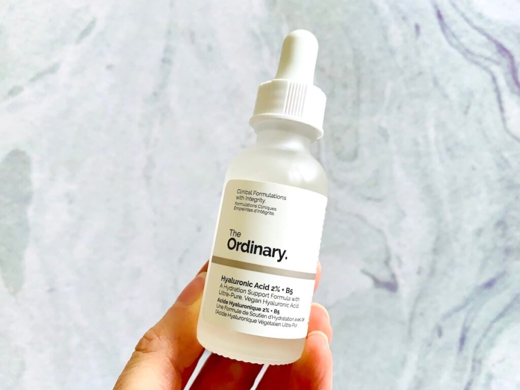 The Ordinary Hyaluronic Acid 2% + B5 Serum handheld in front of a pale blue background.